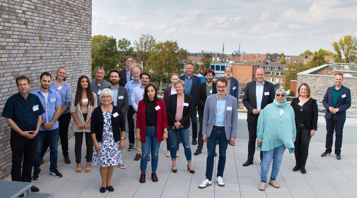 Matthias Hauer MdB und Kai Gehring MdB (Bündnis 90/ Die Grünen, rechts) mit Mitarbeiterinnen und Mitarbeitern des Essener Netzwerks Migrationsberatung für erwachsene Zuwanderer